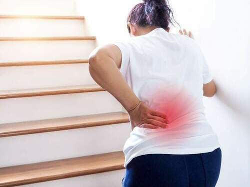 young thai asian woman suffering low back pain waist lumbar pain when walking up stairs